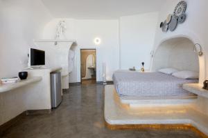 Un dormitorio con una cama y un televisor. en Suites of the Gods Cave Spa Hotel, en Megalokori