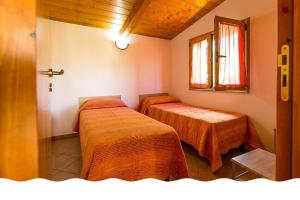 una camera con due letti con lenzuola arancioni e una finestra di Freedom Village a Soverato Marina