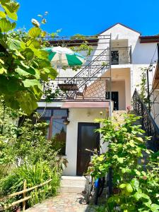 a house with an umbrella and some plants at Гостевой дом Гера in Pizunda