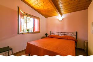 1 dormitorio con cama con sábanas de color naranja y ventana en Freedom Village en Soverato Marina