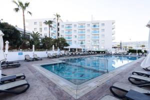 uma grande piscina com espreguiçadeiras e um hotel em Vrissaki Hotel Apartments em Protaras