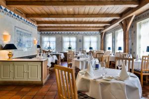 a restaurant with white tables and chairs and windows at Hotel und Restaurant Jörg Müller in Westerland
