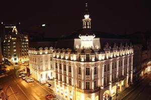 duży budynek z wieżą na górze w nocy w obiekcie Grand Hotel Continental w Bukareszcie