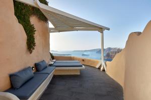 Un balcón con almohadas azules y vista al mar. en Suites of the Gods Cave Spa Hotel, en Megalokori