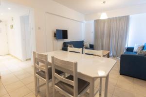 a living room with a table and chairs and a couch at Vrissaki Hotel Apartments in Protaras