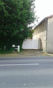 un bâtiment avec une porte blanche à côté d'une rue dans l'établissement chambre d'hôtes proche PUY DU FOU, à Le Pin