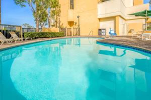 a blue swimming pool with chairs and a building at La Quinta by Wyndham Buena Park in La Palma