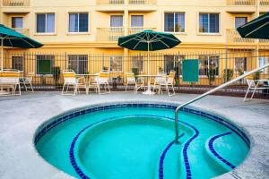 a swimming pool with an umbrella and tables and chairs at La Quinta by Wyndham Tucson Airport in Tucson