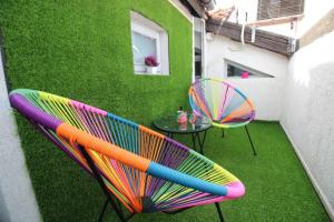 a patio with a table and colorful chairs on the grass at Apartment Happy holiday Lazur in Burgas City