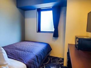 a small bedroom with a bed and a window at HOTEL LiVEMAX Yokohama Stadium Mae in Yokohama