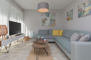 a living room with a blue couch and a tv at Sunny Apartment Łukęcin by Renters in Łukęcin