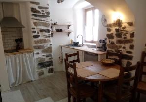 kuchnia ze stołem i kamienną ścianą w obiekcie Charmant Studio dans l’Ancienne Mairie w mieście Saint-Laurent-le-Minier