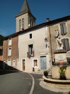budynek z posągiem obok ulicy w obiekcie Charmant Studio dans l’Ancienne Mairie w mieście Saint-Laurent-le-Minier