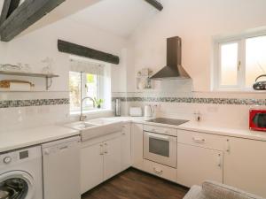 a white kitchen with a sink and a dishwasher at Swift Cottage in Liskeard