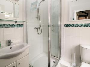 a white bathroom with a shower and a sink at Swift Cottage in Liskeard +12 photos