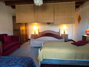 1 dormitorio con 2 camas y sofá rojo en La Grange à outeaux, en Montpont-en-Bresse