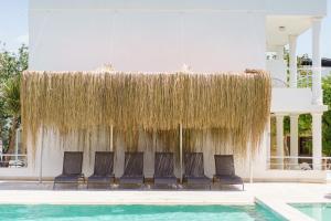 a group of chairs under a straw umbrella next to a swimming pool at Costa Maya Bodrum in Bodrum City