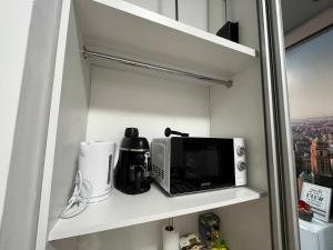 a kitchen shelf with a microwave and a coffee maker at Széchenyi Aparman (II Relax) Miskolc Belvárosában in Miskolc