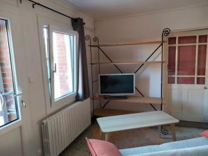 una pequeña sala de estar con TV y mesa. en La Grange à outeaux, en Montpont-en-Bresse