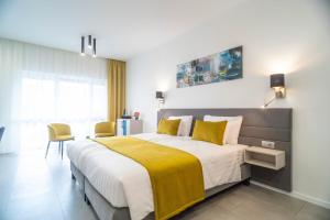 a bedroom with a large bed with a yellow blanket at La Vita Prémium Panzió in Gyula