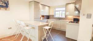 a kitchen with white cabinets and a table and chairs at Top Floor Flat 5 Northwood in Northwood
