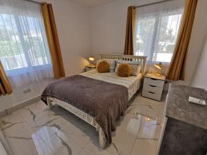 a bedroom with a bed and two windows at Paphos Gardens Apartment in Paphos City +49 photos