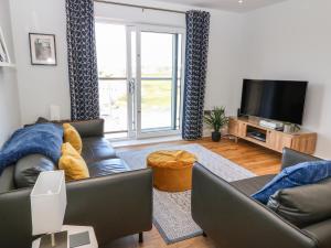 ein Wohnzimmer mit einem Sofa und einem TV in der Unterkunft Beach Apartment 9 in Trearddur