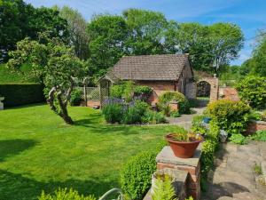 um jardim com uma casa de tijolos e um quintal em The Garden Room, 1 Heath Cottage em Knutsford