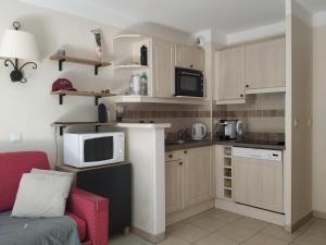 eine kleine Küche mit weißen Schränken und einem roten Stuhl in der Unterkunft Les Coteaux B10 in Mallemort