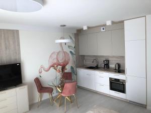 a kitchen with white cabinets and two chairs and a tv at Rogowo Pearl 1510 in Rogowo