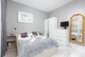 a white bedroom with a bed and a mirror at Mokotow Business Center Apartments by Renters in Warsaw