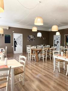 un restaurante con mesas de madera y sillas blancas en Green Gallery Hotel and Restaurant, en Muravera