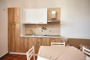 uma cozinha com armários brancos e uma mesa com cadeiras em A casa di Emma em Vietri