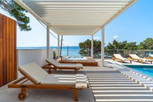 una terraza al aire libre con tumbonas y una piscina en New! Villa Bava with 4 En-suite Bedrooms, Heated 33 sqm Pool en Omiš