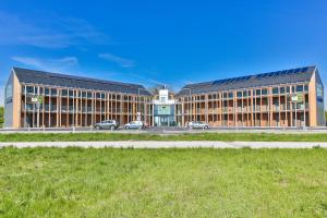 un grand bâtiment avec des voitures garées devant lui dans l'établissement Motel Verde, à Schönau an der Triesting