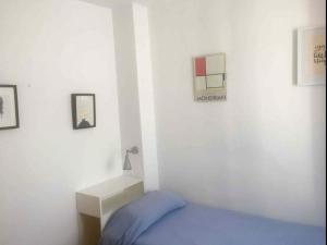 a bedroom with a blue bed and a white wall at Apartamento luminoso y acogedor Port de la Selva in Port de la Selva