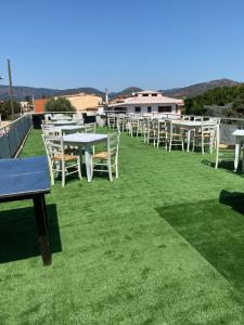 a row of tables and chairs on a lawn at Green Gallery Hotel and Restaurant in Muravera