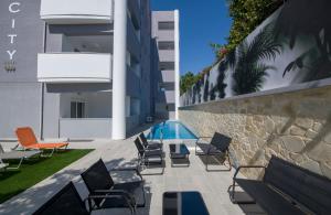 eine Terrasse mit Stühlen und einen Pool neben einem Gebäude in der Unterkunft Deluxe City Hotel in Chania