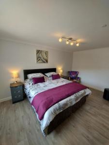 a bedroom with a large bed with purple sheets at Glenwood luxury Cottage Betws-y-coed in Betws-y-coed