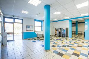 a large room with blue columns and a tiled floor at Ostello Ipsia in San Benedetto del Tronto