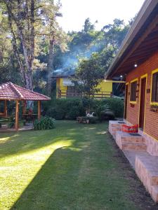 einen Hinterhof eines Hauses mit einem Rasenplatz in der Unterkunft Cháles Terra Nativa in Monte Verde