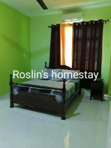 ein Schlafzimmer mit einem Bett in einem grünen Zimmer in der Unterkunft Roslin's Homestay in Kota Bharu