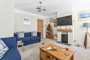 a living room with a blue couch and a tv at Captains Cottage - Stylish cottage, level location, in the heart of Dartmouth in Dartmouth