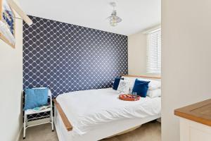 a bedroom with a bed and a blue and white wall at Captains Cottage - Stylish cottage, level location, in the heart of Dartmouth in Dartmouth