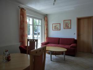 ein Wohnzimmer mit einem roten Sofa und einem Tisch in der Unterkunft Ferienwohnung T7 in Graal-Müritz