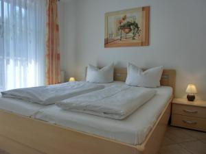 ein Bett mit weißer Bettwäsche und Kissen in einem Schlafzimmer in der Unterkunft Ferienwohnung T7 in Graal-Müritz