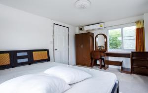 een slaapkamer met een wit bed en een bureau bij Baan Sin Suk in Chiang Rai