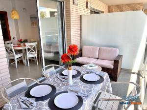 a table with plates and a vase with flowers on it at APARTBEACH PANORAMIC VISTAS PLAYA y PISCINA in Miami Platja