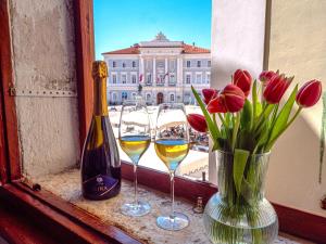 ein Fenster mit zwei Gläsern Wein und einer Vase Blumen in der Unterkunft Artini Apartments Piran in Piran