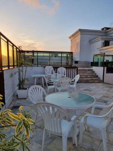 um pátio com cadeiras brancas e uma mesa na varanda em Loft Beira Mar Prainha wi-fi 600 megas apt 323 em Arraial do Cabo